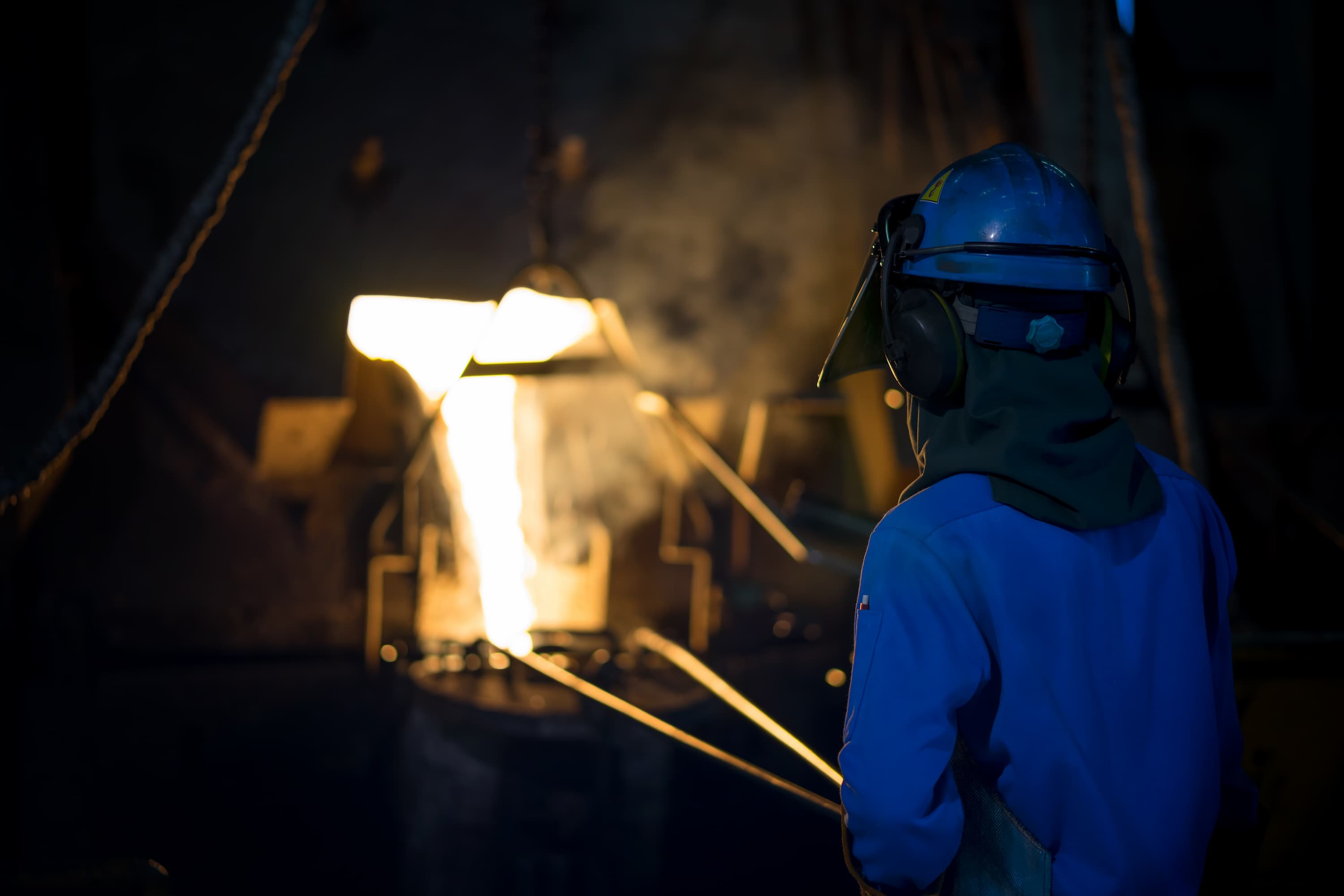 Engineer pouring metal casting parts from a ladle in a foundry to perfect gas porosity.