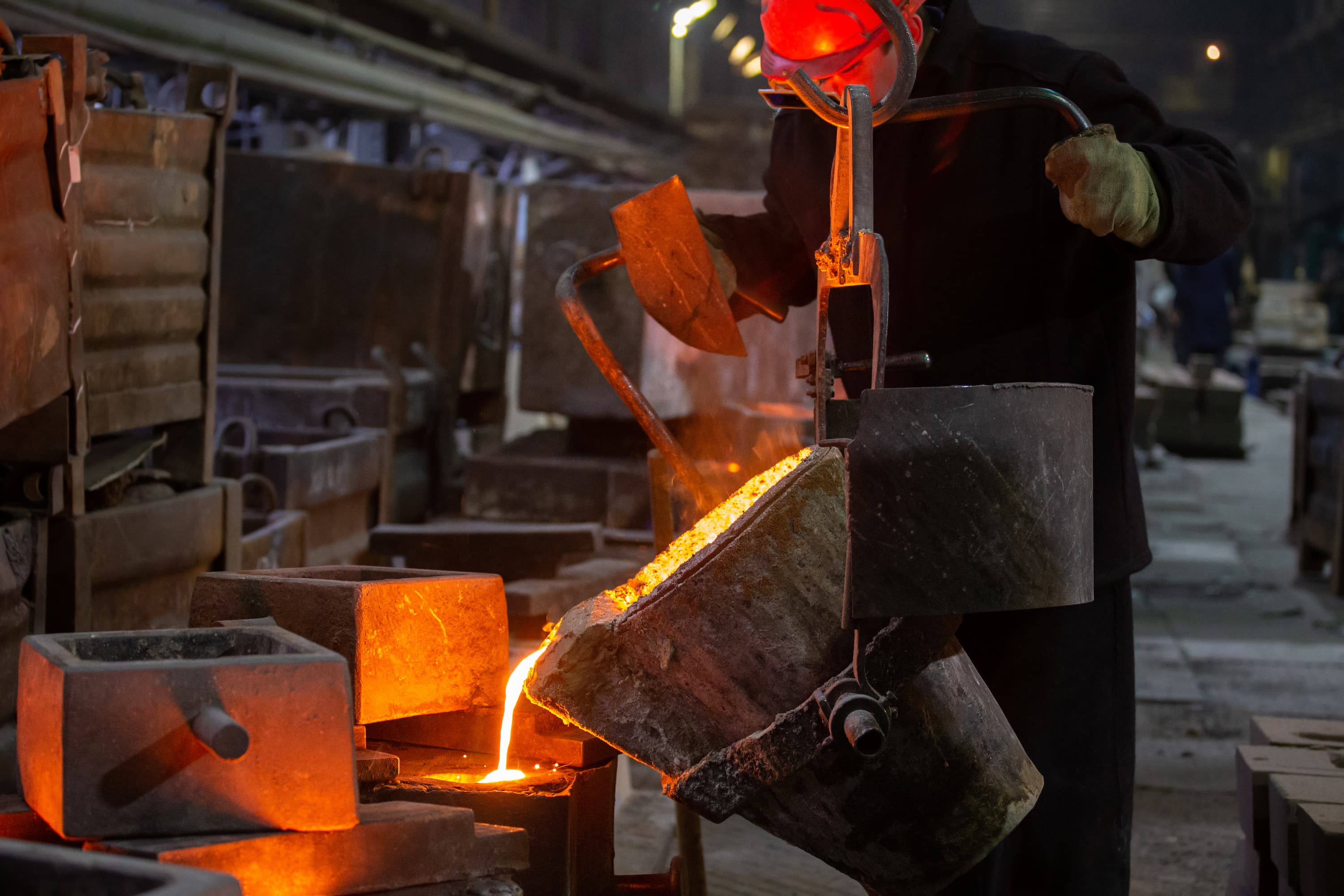 Worker filling high-pressure die casting mold with molten metal.