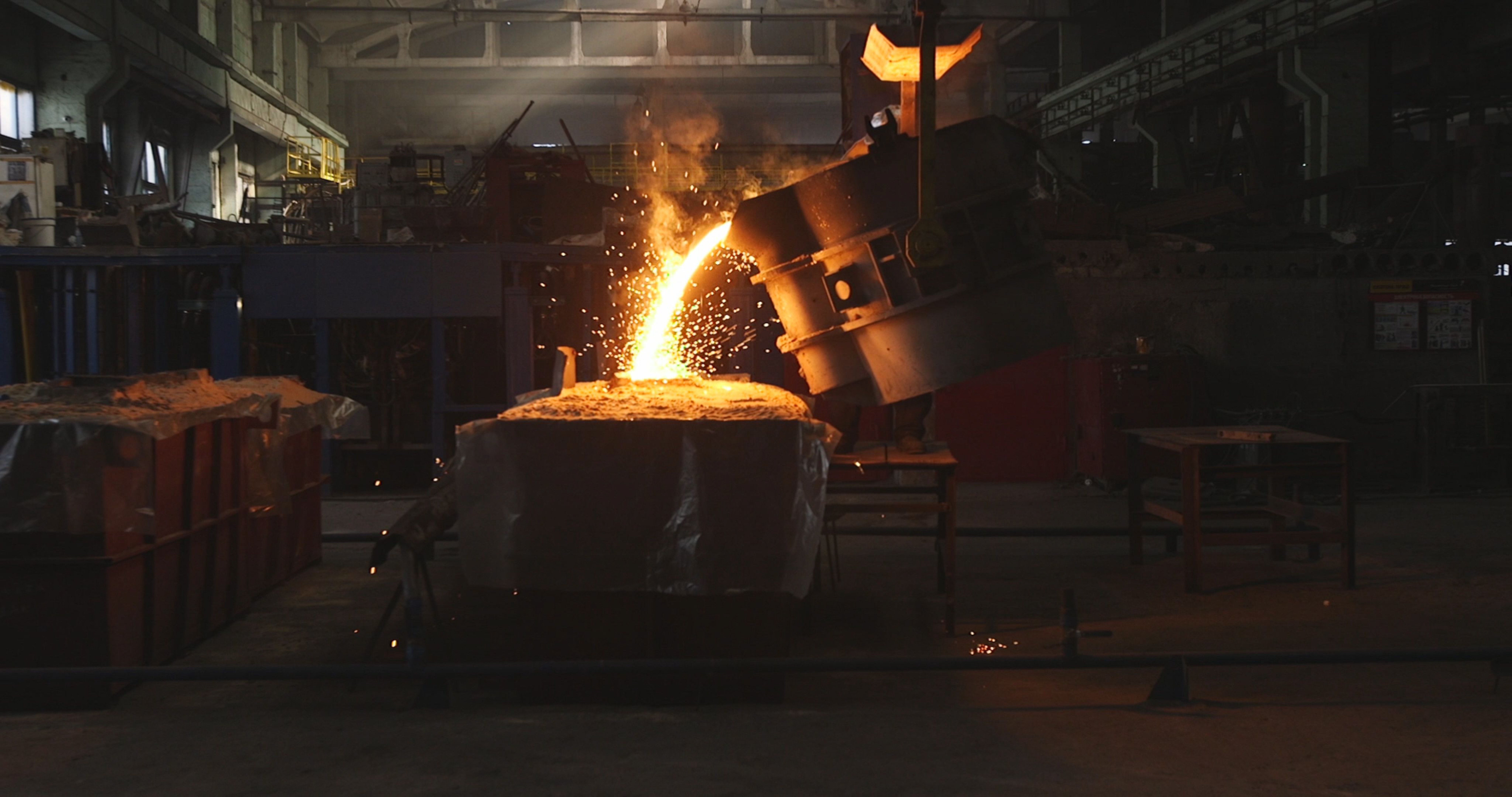 Liquid metal from ladle pouring in castings at a factory.