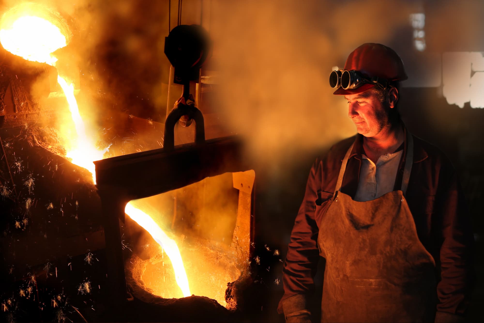 Production worker in a foundry with a melting iron works to alleviate metal warping.